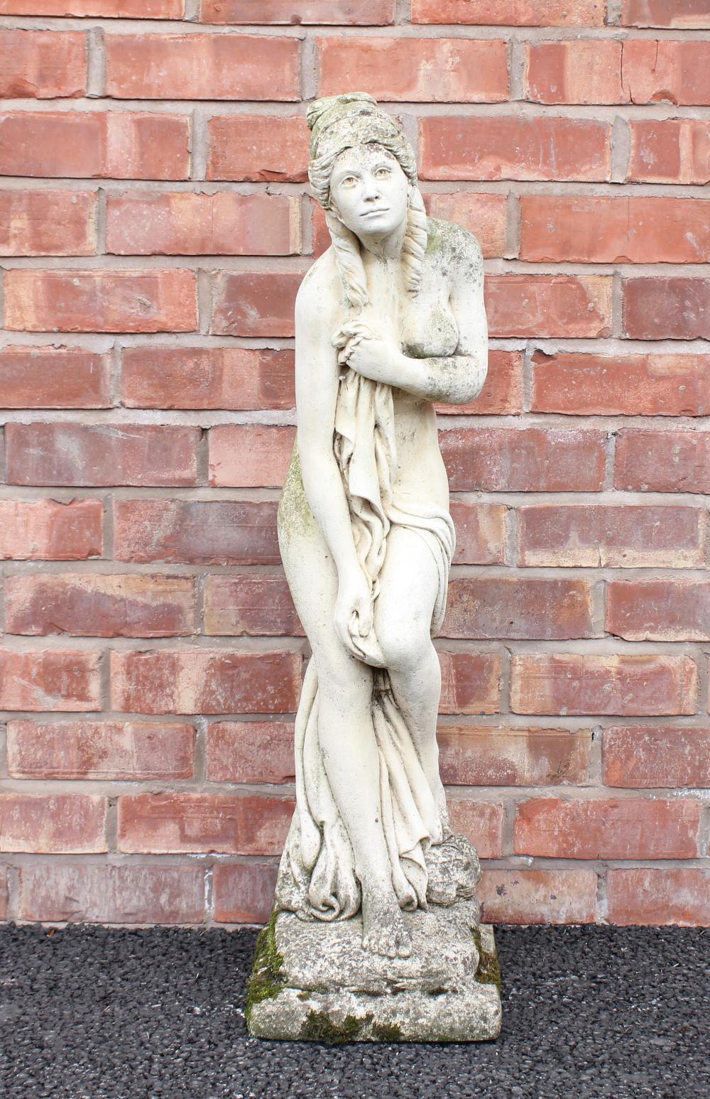 A reconstituted stone garden statue, modelled as a classical scantily clad female upon an integrated