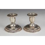 A pair of silver mounted desk candlesticks, each on weighted circular bases with scrolling floral