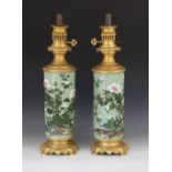 A pair of Chinese porcelain and ormulu mounted oil lamps, each cylindrical body decorated with