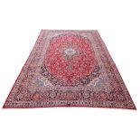 A large hard woven Persian Kashan carpet, with scrolling floral medallion in navy and white