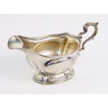 A George V silver sauce boat by Carrington & Co, London 1913, of shaped oval form on pedestal foot
