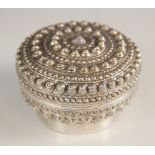 A Chinese silver coloured box and cover, of circular form on raised foot, elaborately decorated with