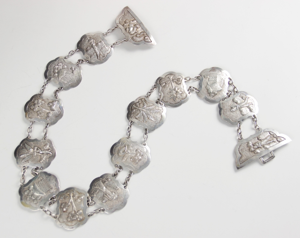 An Asian silver coloured belt, each lozenge shaped link with scalloped borders, embossed with