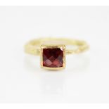 A garnet set 18ct gold ring by Disa Allsopp, the central square briolette cut garnet measuring 5.5mm