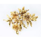 An 18ct gold floral spray brooch, designed as three stylised flower heads amongst a foliate