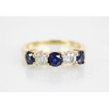 A sapphire and diamond five stone ring, the central round mixed cut blue sapphire measuring 4.6mm