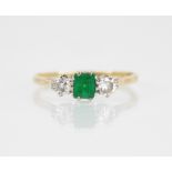 An emerald and diamond three stone ring, the central rectangular step cut emerald measuring 4.5mm