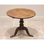 A George III oak tripod table, the circular top raised upon a baluster column extending to three