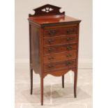 An Edwardian mahogany and rosewood crossbanded music cabinet, the pierced architectural pediment