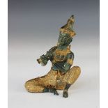 An Indian patinated bronze and gilt model of Krishna, 20th century, modelled seated playing a flute,