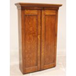 A late Victorian oak gun cabinet, the moulded cornice above a pair of panelled doors opening to a