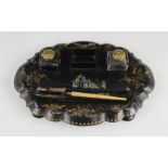 A Victorian papier mache desk tidy, of oval form with shaped border, raised on four feet, with