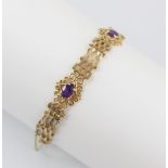 A gold coloured amethyst set bracelet, the gate-link bracelet interspersed by three pierced