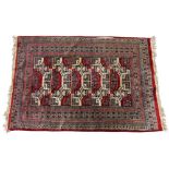 A Persian pattern rug, with five central geometric bands in red and white colourways, enclosed by
