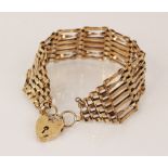 A 9ct gold gate link bracelet, 18cm long, 25mm wide, suspending a 9ct gold heart -shaped padlock