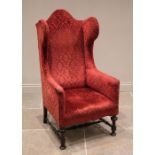 A William and Mary style wing back armchair, early 20th century, in embossed red foliate fabric, the