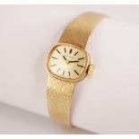 A ladies vintage 9ct gold Bulova wristwatch, the cushion shaped dial with black baton markers, set