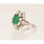 An emerald and diamond ring, the central rectangular step cut emerald measuring 9.7mm x 8.0mm, set