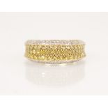 A white and yellow diamond 14ct gold ring, the central recessed pave set with three rows of coloured