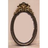 A 19th century ebonised, giltwood and gesso oval wall mirror, the frame surmounted with a gilt lions