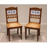 A pair of Victorian golden oak tile back hall chairs, each chair with a foliate carved top rail