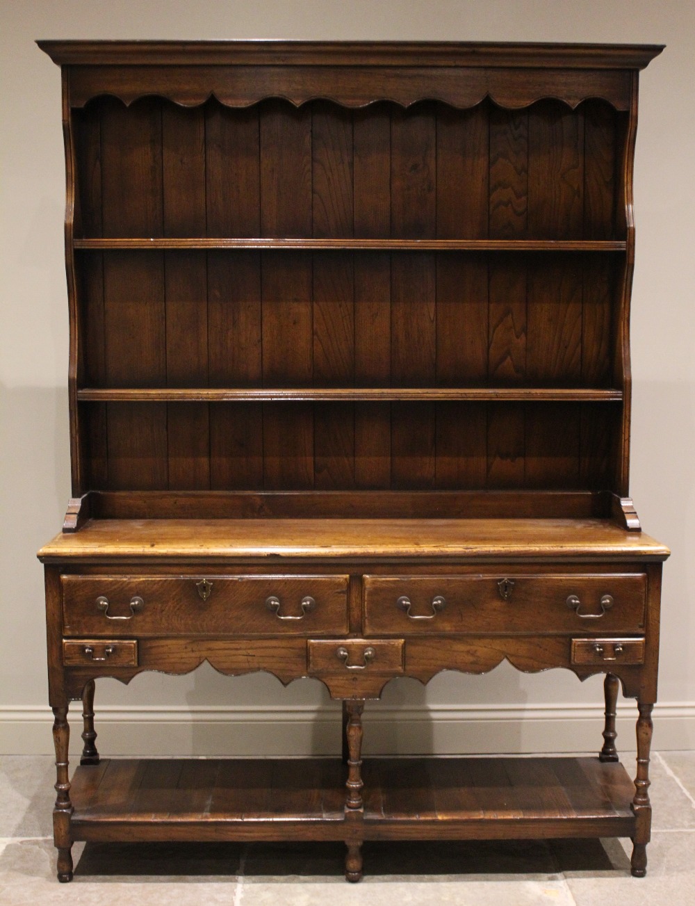 A George III style oak dresser, late 20th century, the moulded cornice above a scalloped frieze