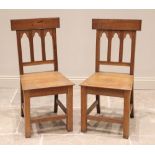 A pair of honey oak altar/hall chairs, 20th century, each with a rail back over a board seat, raised
