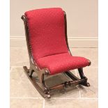 A Victorian mahogany framed rocking chair, the upholstered back and seat raised upon out swept