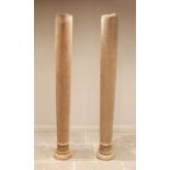 A pair of architectural pine columns, each of tapering cylindrical form, with circular capitals