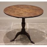 A George III oak tripod table, the circular plank top raised upon a baluster column extending to