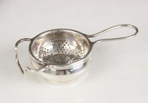 A George V silver tea strainer and stand, W J Myatt & Co, Birmingham 1933, the circular bowl with
