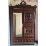 A late 19th/early 20th century French carved oak armoire, the shaped pediment centred with an
