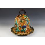 A majolica cheese bell in the manner of Minton, modelled as a bee skep entwined with fruiting vines,