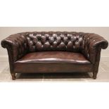 An early 20th century oak framed Chesterfield sofa, with typical deep set button back and arms,