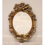 A 19th century style gilt and composite oval wall mirror, the bevelled plate within a scrolling