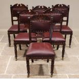 A set of six late Victorian walnut and red leather dining chairs, the carved crest rail above