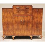 A 1930's figured walnut cocktail cabinet, of angular form, the central fall front enclosing a