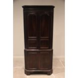 A George III mahogany freestanding corner cupboard, the moulded dentil cornice above a blind