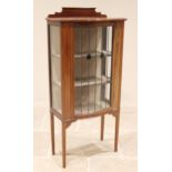 An Edwardian mahogany display cabinet, with a shaped rear gallery above a bowfront leaded and