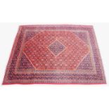 A large red ground Persian Sarouk carpet, in red, blue and green colourways, with an all over