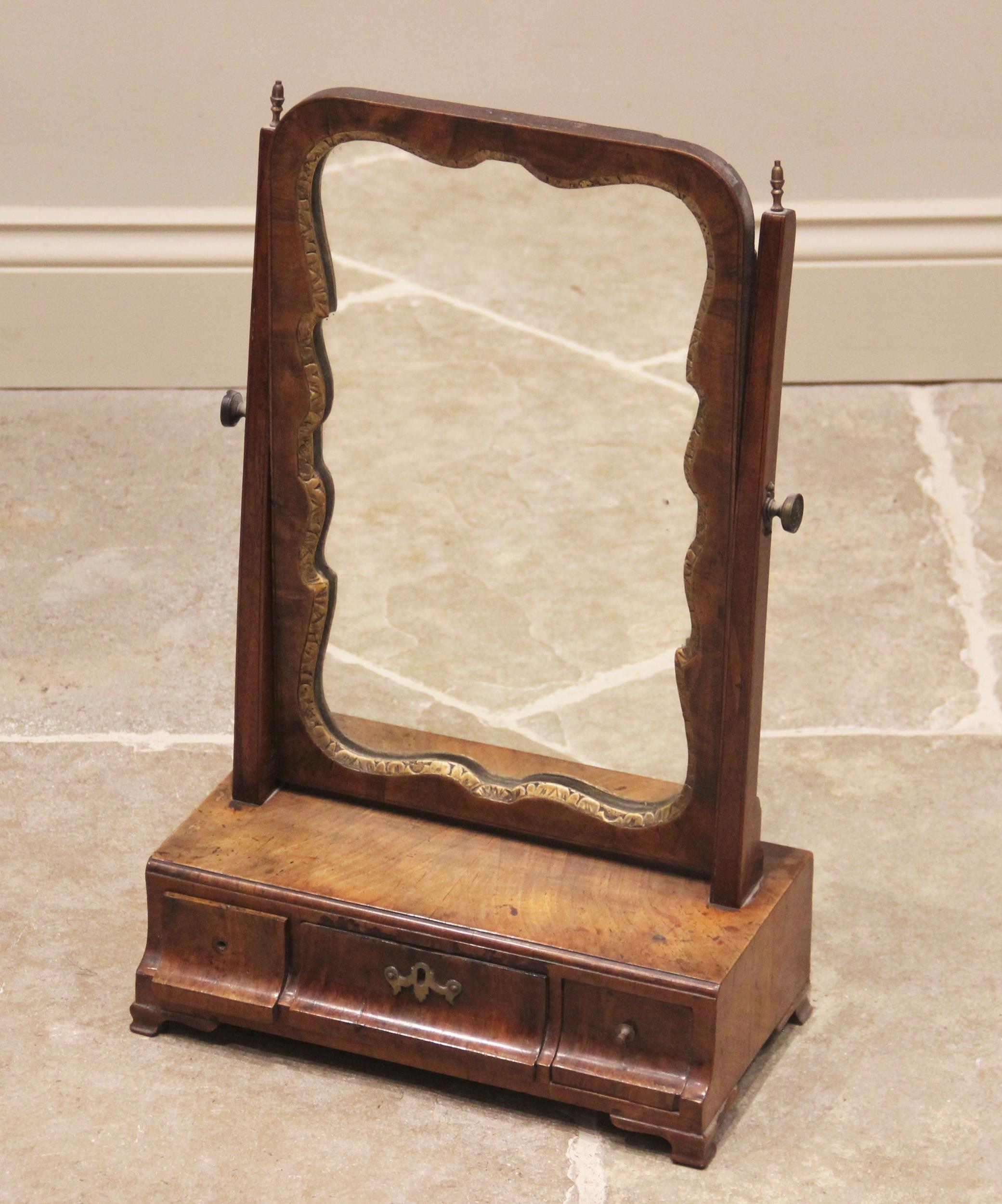 A George II walnut toilet mirror, the mirrored plate with a shaped parcel gilt border, on tapering