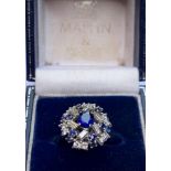 A sapphire and diamond cluster ring, the central oval mixed cut sapphire measuring 6mm x 5mm, within