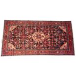 A deep ground Hamadan village rug, in red, blue and ivory colourways, the all over floral design