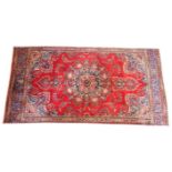 A vintage red ground Persian Tabriz wool rug, the central floral medallion upon a vibrant red