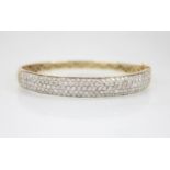 A diamond set 9ct gold hinged bangle, of oval form, the front section set with one-hundred and