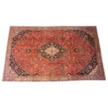 A washed red ground fine woven Persian Kashan, the floral medallion upon a red ground embellished