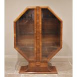 A 1930's Art Deco octagonal walnut display cabinet, the pair of glazed doors opening to two glass
