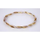 A 9ct gold bi-colour twist design hinged bangle, designed as an interwoven plain polished yellow