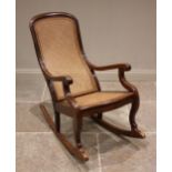 A Victorian mahogany and rattan rocking chair, the arched cane back extending to down swept arms