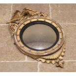 A Regency gilt wood and gesso wall mirror, the convex circular mirrored plate within an ebonised and